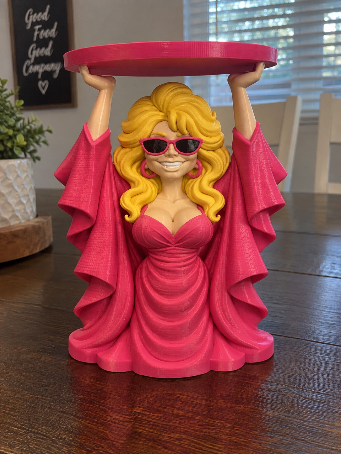 Dolly Parton candle holder preview with blonde hair, pink sunglasses and gown, and a pink circular tray held overhead.