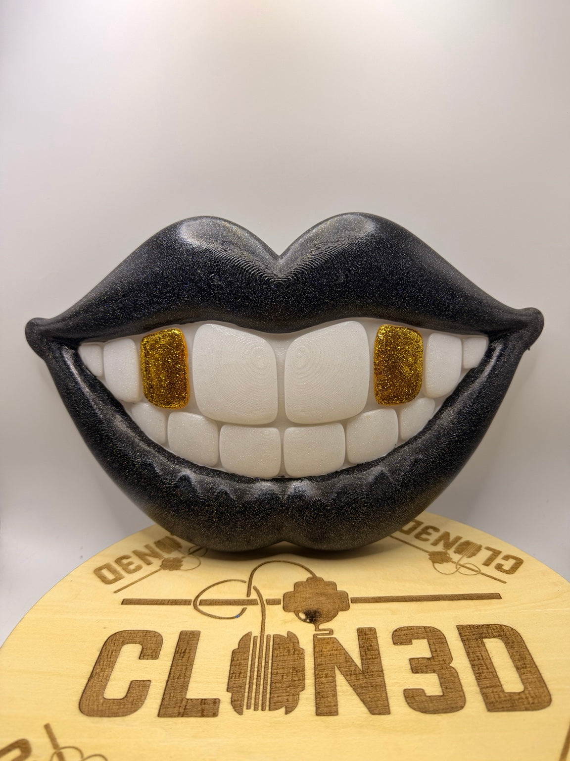Black smiling lips wall artwork with white teeth and gold glitter tooth accents
