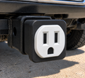 Black-and-white electrical outlet-style decorative tow hitch cover installed in a vehicle's hitch receiver.