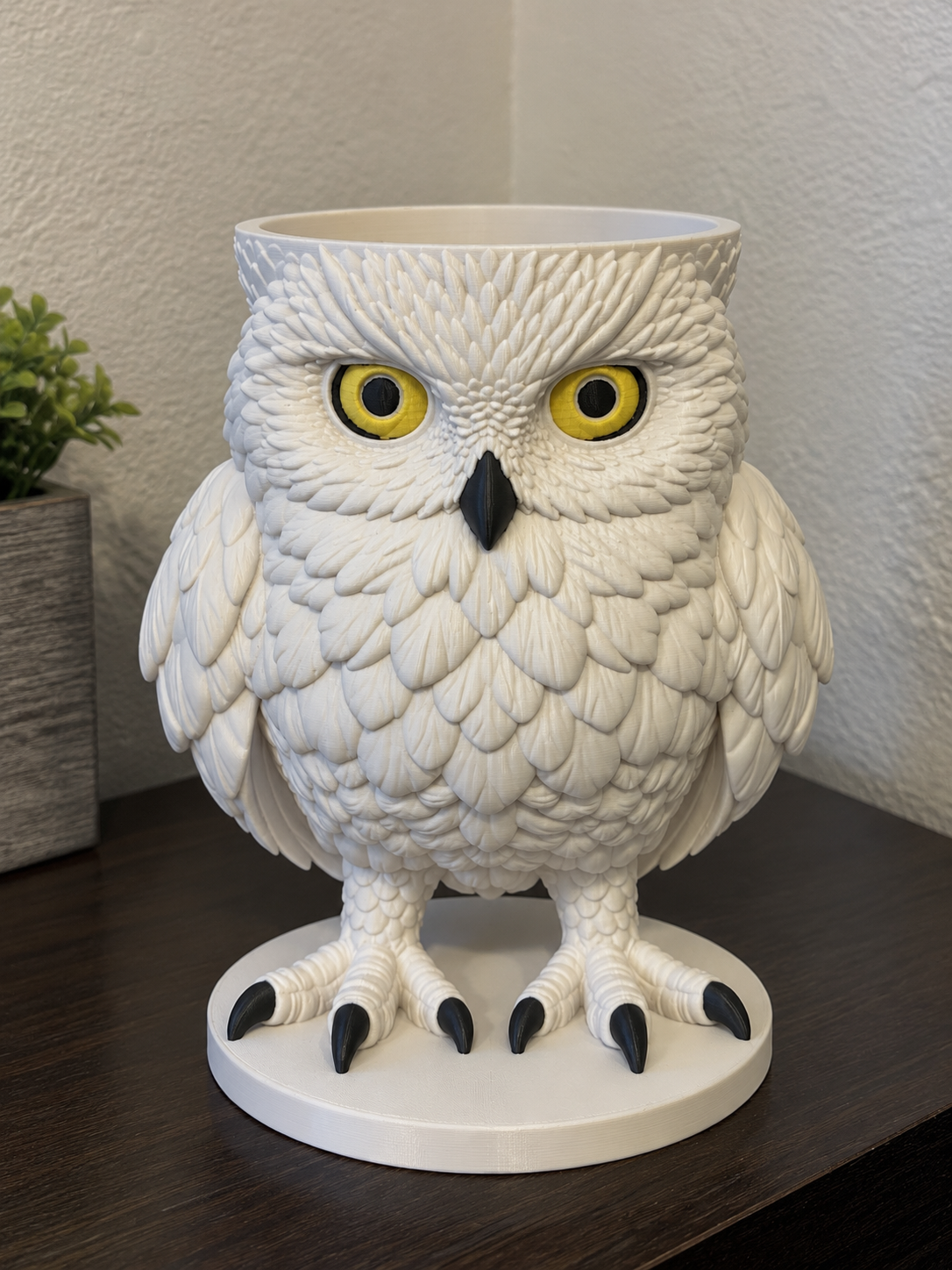 White Hedwig owl candle holder with yellow eyes, black beak and talons, and a round base.