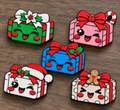 Five smiling Christmas present ornament designs with festive bows, holly, a candy cane, Santa hat and gingerbread detail