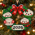Christmas wreath ornament with festive dumpling characters, a red bow, green holly and a 2026 plaque
