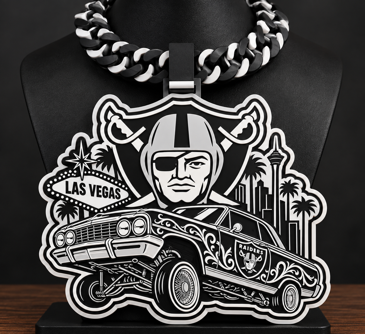 Black-and-white Raiders lowrider hype chain with Las Vegas landmarks on a black display bust.