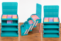 Three views of a teal four-tier vendor display rack with slotted back panel and pink side supports, shown as a digital STL preview.