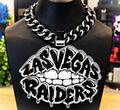 Black-and-white Las Vegas Raiders Lip hype chain with teeth and dripping graffiti-style lettering on a black display bust.