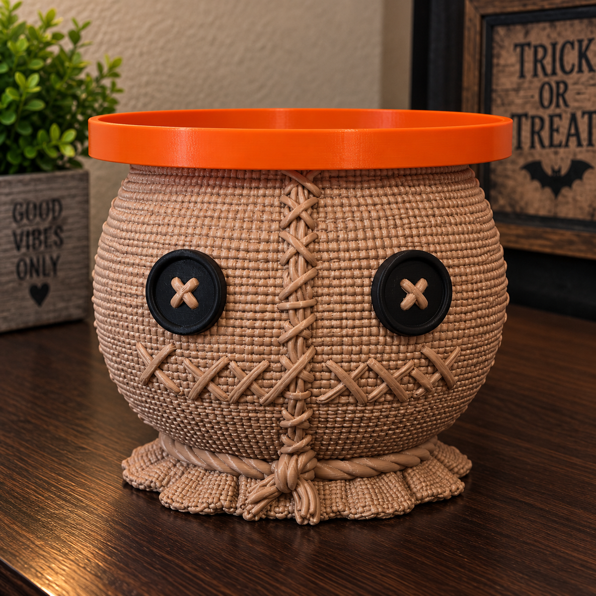 Sam candle holder with burlap-style texture, black button eyes, stitched details, and an orange circular top tray.