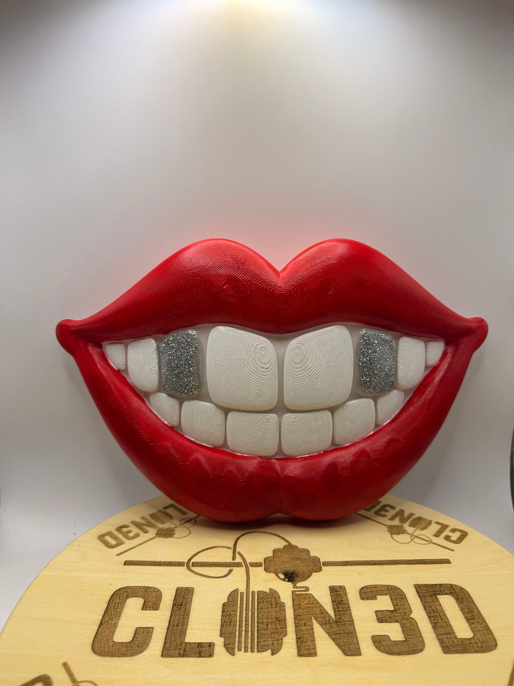 Red smiling lips wall artwork with white teeth and silver glitter tooth accents