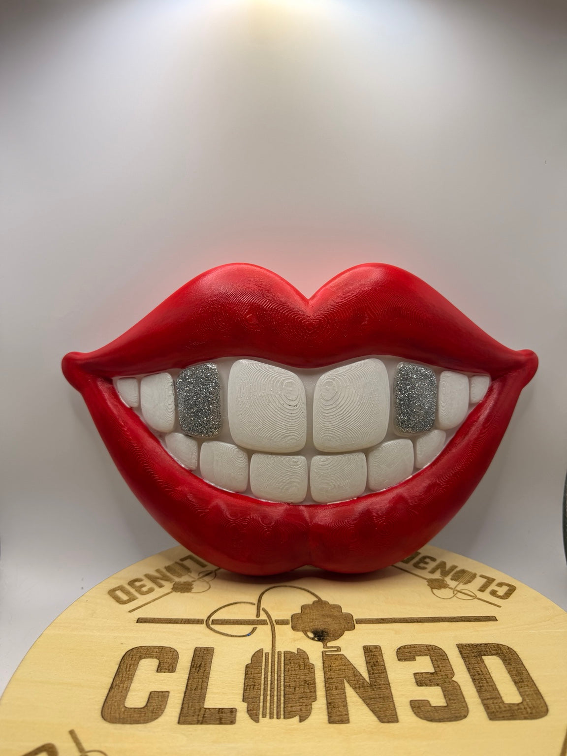 Red smiling lips wall artwork with white teeth and silver glitter tooth accents